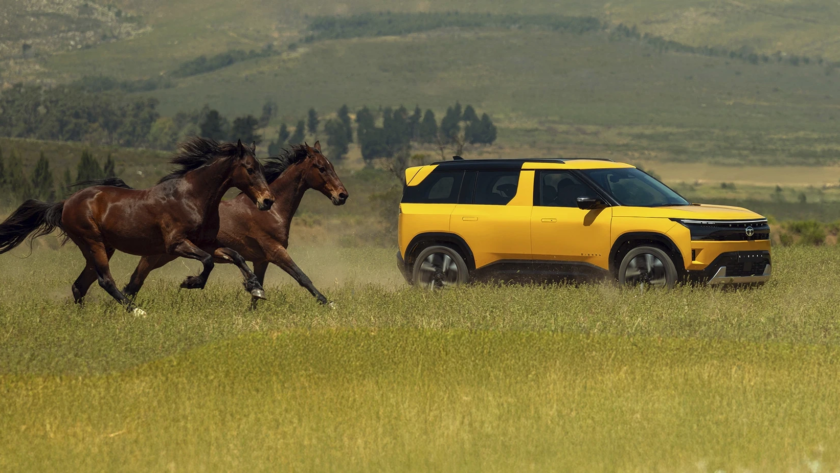 A yellow and black dual-tone new-generation Tata Sierra SUV driving on an outdoor, grassy plain with some horses galloping behind it.