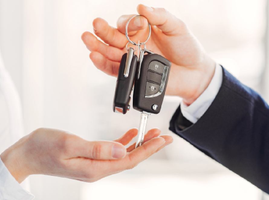 Close-up of a person handing over car keys to another person, symbolising car sale or resale transaction.