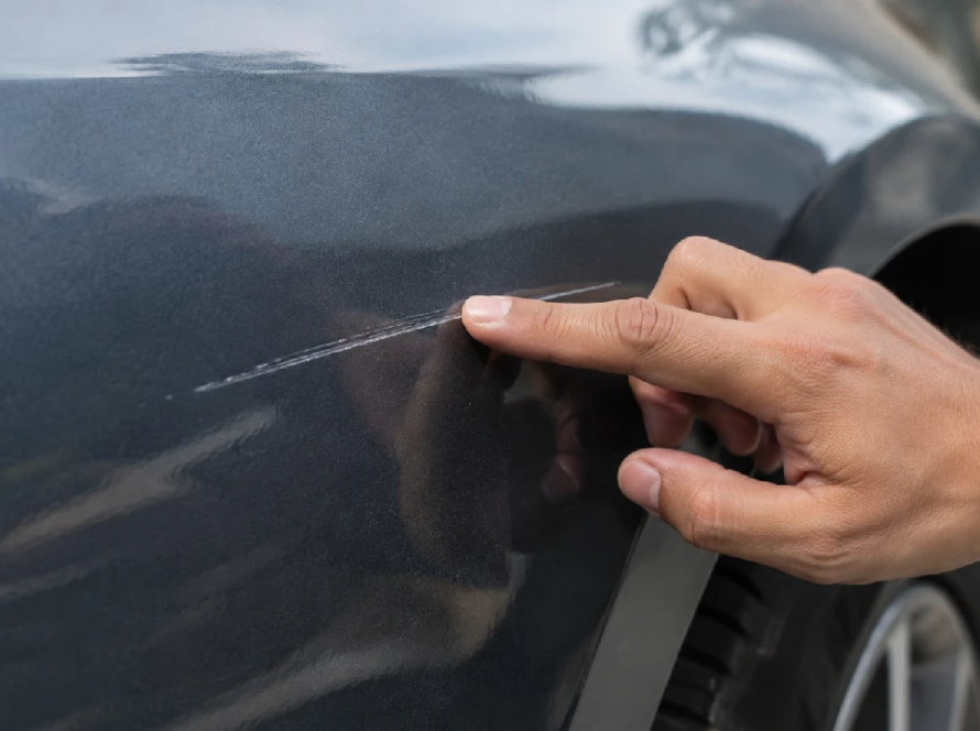 Hand testing the depth of a car paint scratch
